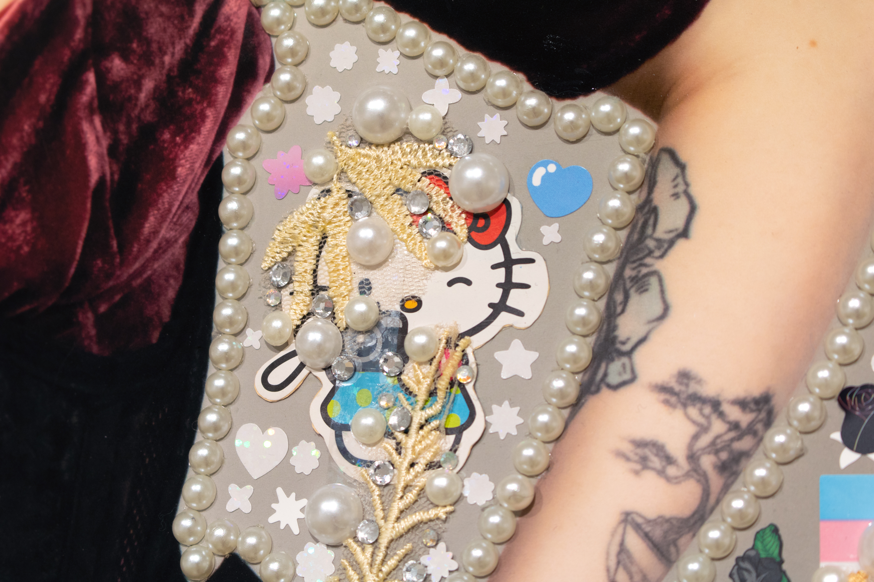 detail of 'pearl' piece featuring a close-up of a sticker of hello kitty holding a camera and looking through the viewfinder, surrounded by pearls