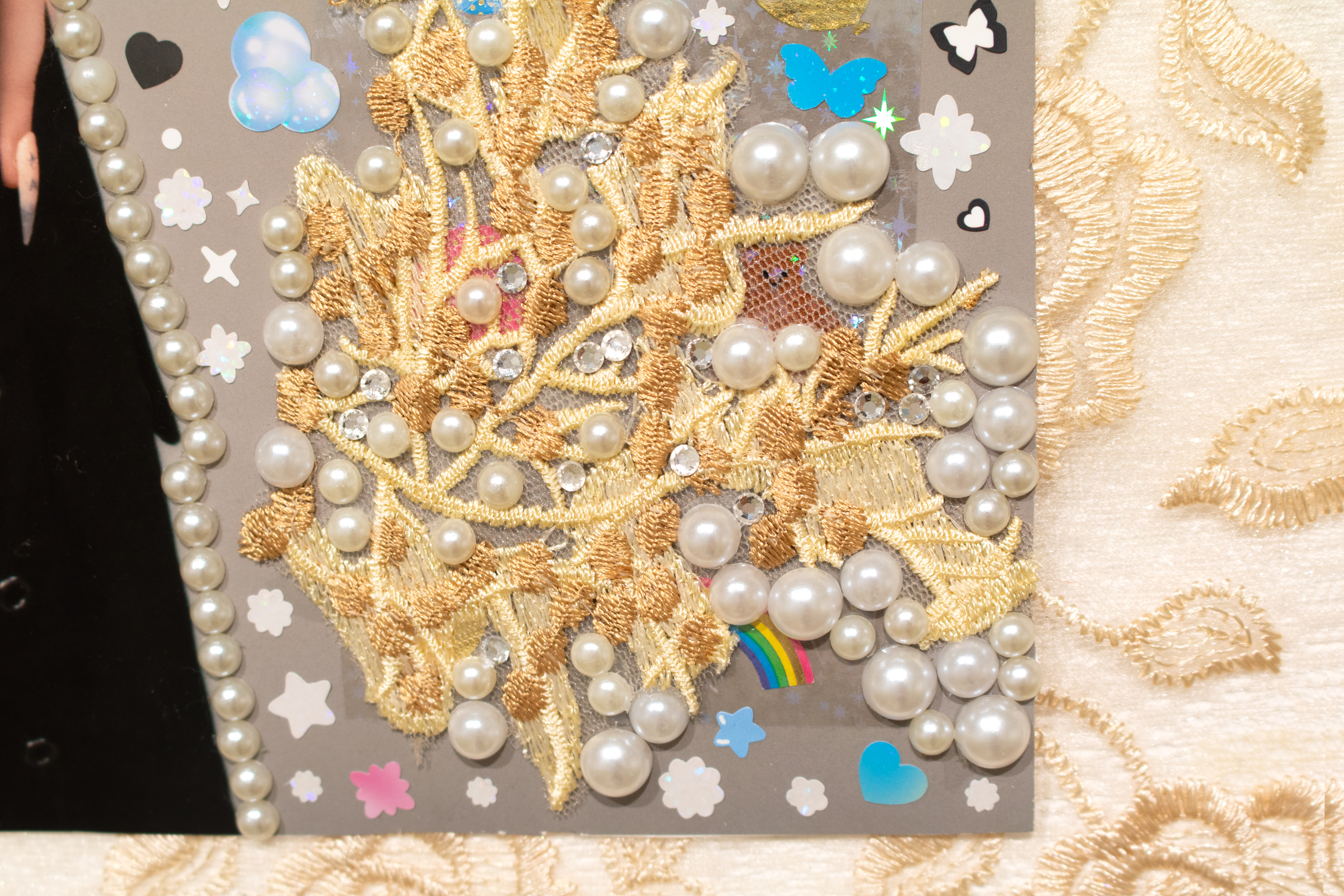 detail of 'pearl' piece featuring a close-up of a piece of lace embellished with pearls and surrounded by decora-style stickers